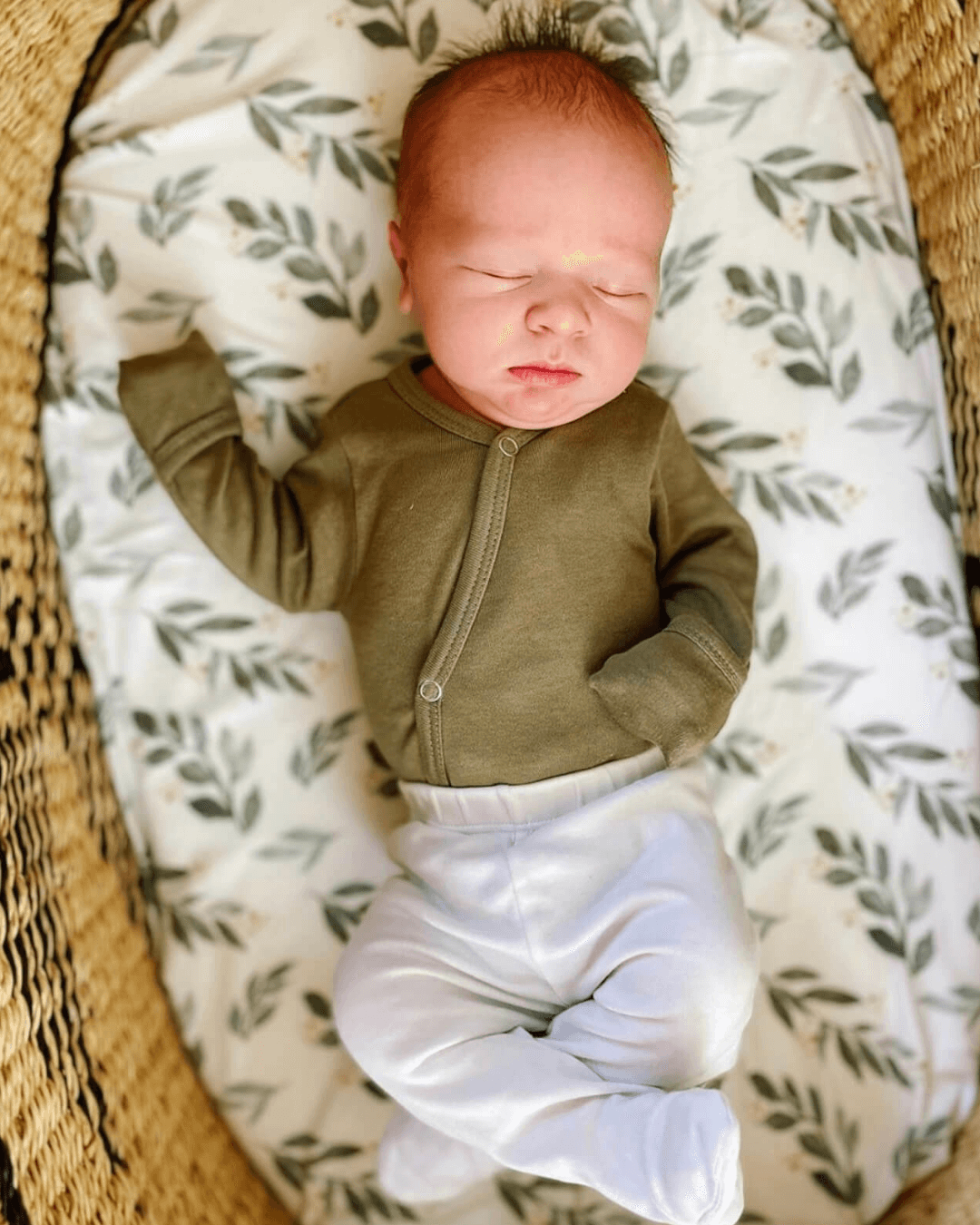 A woman laying down with her newborn baby and smiling